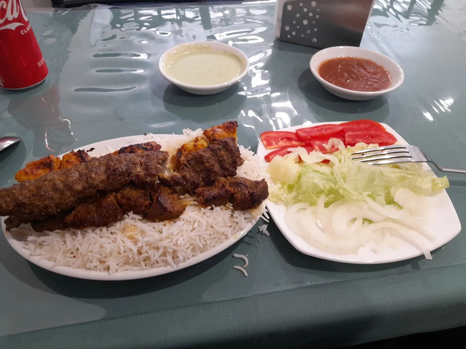 Mixed kebab plate with flame-grilled beef and chicken skewers, rice, salad, and house sauces